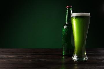 glass of green beer with bottle on wooden table, st patricks day concept