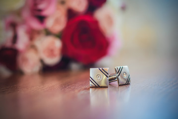 Cufflinks for sleeves next to the wedding bouquet