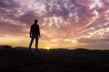 Fototapeta premium A young man traveler standing enjoy with beautiful sunset on top of the mountain.