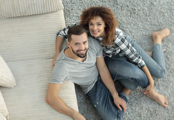 young couple sitting on the carpet in the new living room