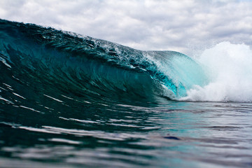 moody blue wave crashing over shallow reef