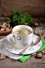 Delicious healthy soup with fresh and dried mushrooms in a cup on an old wooden background.