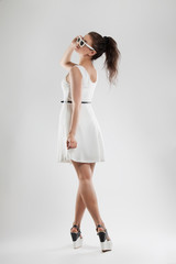 fashion portrait of a woman. a young beautiful girl in a light white dress posing in the Studio. Sunglasses.