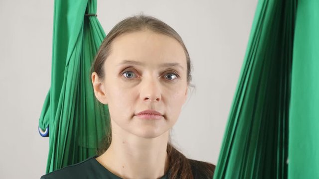 Portrait of young beautiful fly yoga confused, at a loss. Aerial aero fly fitness trainer workout. Meditates, harmony and serenity concept, close up, portret 60 fps