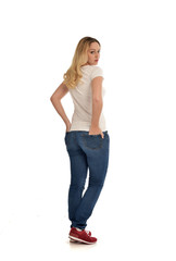 Fototapeta premium full length portrait of blonde girl wearing simple white shirt and jeans, standing pose, isolated on white studio background.