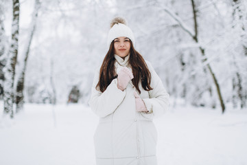 A beautiful and fashoin woman in white warm clothing walking in snowy weather.