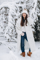 A beautiful and fashoin woman in white warm clothing walking in snowy weather.