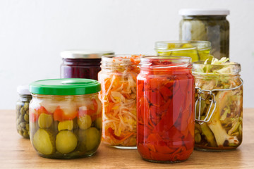Fermented preserved vegetables in jar on wooden table.