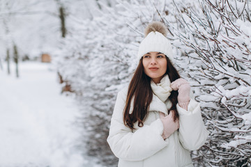 A beautiful and fashoin woman in white warm clothing walking in snowy weather.