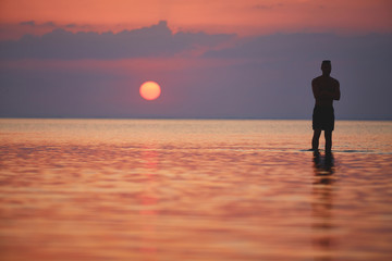 Fototapeta premium silhouette of athletic man against the sea and sunset. happy man enjoying summer vacation