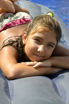 Portrait of a girl in bikini sunbathing on an inflatable mattress in swimming  pool