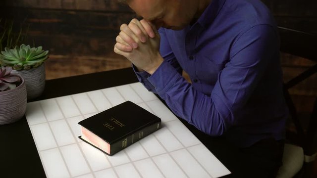 Praying man opens bible and reads