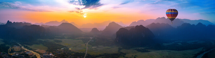 Aerial view of Vang vieng with mountains and balloon at sunset.