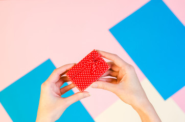 Stylish flat lay with woman hands wrapping holding present. Holiday celebration concept woman hands opening red gift box.