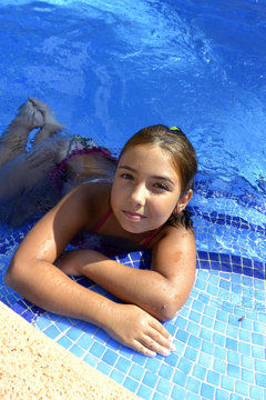 Wet girl after swimming resting on the steps of the pool