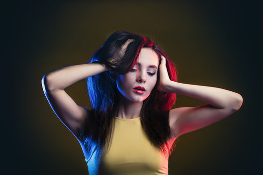Young beautiful portrait model posing on yellow background in Studio in top, with blue and red backlight