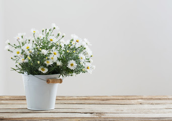white flowers on bucket on wooden table © Maya Kruchancova