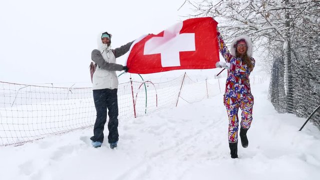National flag of Switzerland waving in the wind with blurred mountains in the background