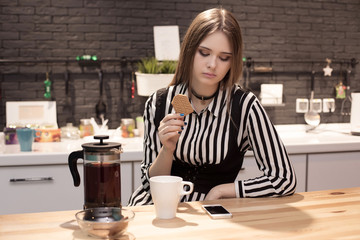 Young beautiful woman is sitting in the kitchen and looking at the phone, social network, chatting...