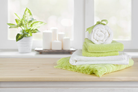 Spa towels on wooden table over blurred salon window background