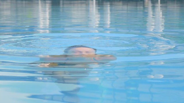 Young attractive girl in swimming pool dive and pops up