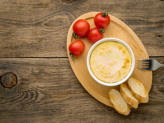 wood plate with oven-baked omelet of eggs and milk, with  tomatoes and toast on brown rustic wooden table, top view, copy space