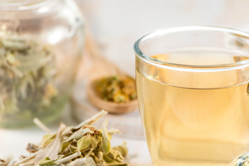 Medicinal tea in glass cup with dried herb.