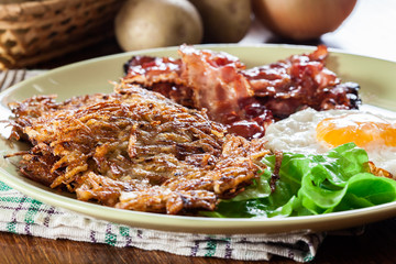 Hash browns. Potato pancakes with crispy fried bacon and fried egg