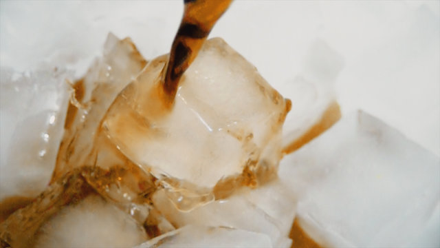 Pouring cola into ice with bubbles