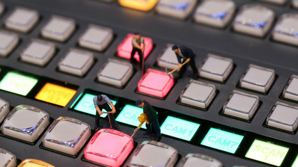 Miniature people : worker on switcher control of Television Broadcast,color buttons.