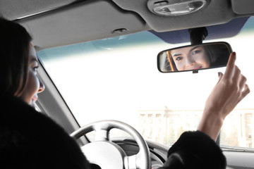 Woman adjusting rear view mirror in car