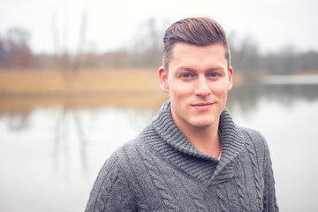 handsome blond man in front of lake