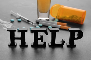 Composition with word "Help", drugs, cigarettes and alcohol on grey background