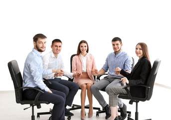 Group of young people holding hands together on chairs, indoors. Unity concept