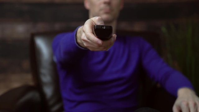 Man picks up tv remote and presses button