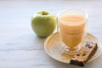 Glass of juice, cereal bar and apple on table. Tasty breakfast