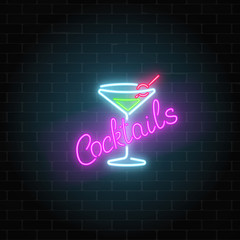 Neon cocktails bar or cafe sign on dark brick wall background. Glowing gas advertising with glass of alcohol shake.