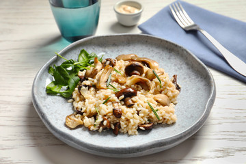 Plate with delicious risotto and mushrooms on table