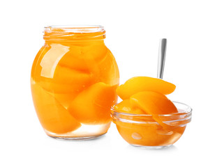Jar and bowl with pickled apricots on white background
