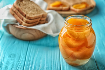 Jar with pickled apricots on table