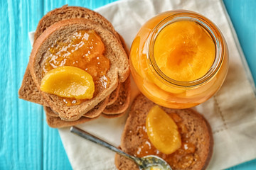Jar and slices of bread with pickled apricots on table