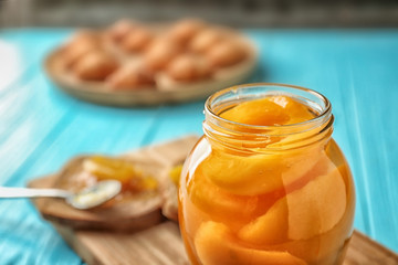 Jar with pickled apricots on wooden board
