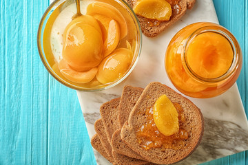 Slices of bread, bowl and jar with pickled apricots on table