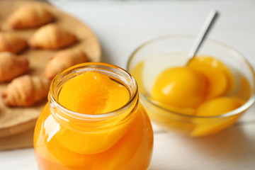 Jar with pickled apricots on table
