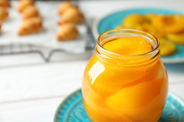 Jar with pickled apricots on plate