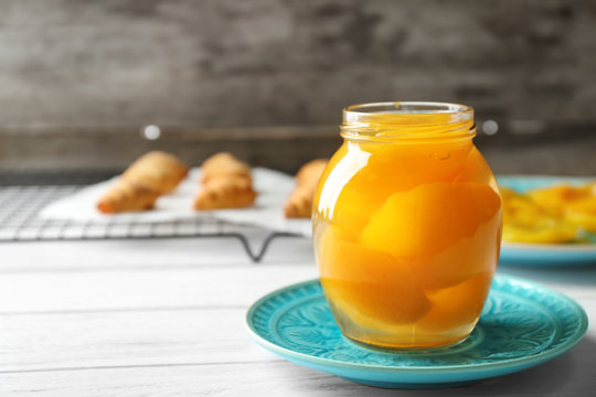 Jar with pickled apricots on plate