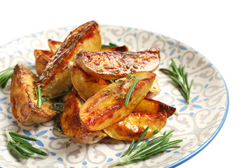 Plate with tasty potato wedges on white background