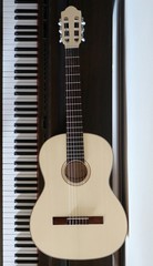 Fototapeta premium Gitara akustyczna z jasnego drewna obok klawiatury fortepianu