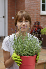 Mujer joven con plantas delante de su casa