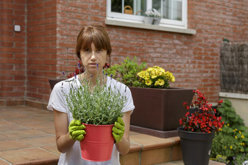 Mujer joven con plantas delante de su casa